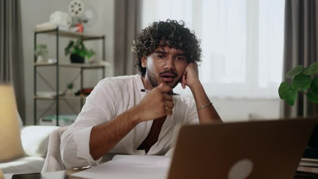Tired exhausted stressed young indian man student preparing for exams and looking at scope of work with sad face at home workplace Overwork education concept