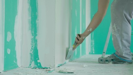 Man Painter Applying Putty on Wall with Trowel During Renovation