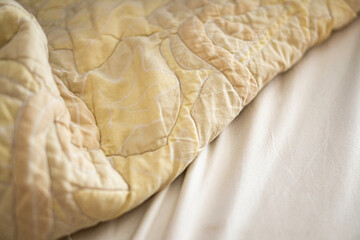 Wrinkled Yellow Blanket on White Bed Sheet