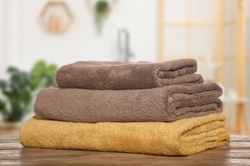 Folded fresh towels on wooden against blurred bathroom interior