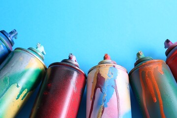Many spray paint cans on light blue background