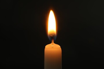 One burning church candle on black background, closeup