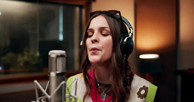 Woman, musician and singer in music studio for song recording with microphone for voice control. Female person, talent and passionate artist with headphone on singing for album or playlist and audio