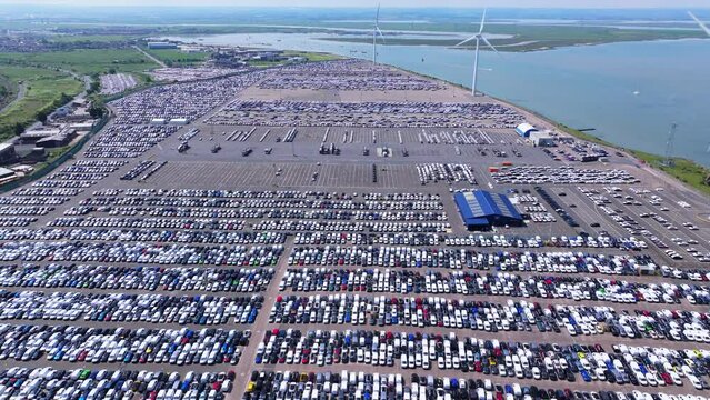 An aerial shot slowly flying over thousands of cars waiting for export from Sheerness Docks, UK