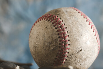 Old used baseball ball closeup with blue texture background.