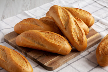 Mini baguettes on a wooden board, side view.