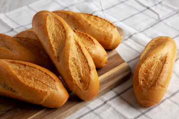 Homemade Mini baguettes on a wooden board, side view.