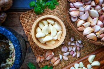 Peeled garlic in a wooden bowl and garlic background,  top view table