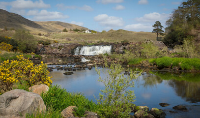 Fototapeta premium A waterfall in the distance with the water reflecting the sky and plants