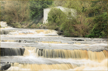 Orange brown water flowing over some waterfalls