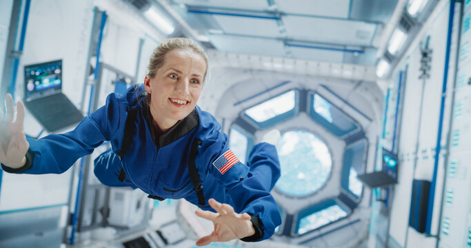 Female Astronaut in Blue Spacesuit Floating Inside the International Space Station, Smiling. Demonstrates Human Achievement in Space Exploration. Cosmos Inspires  Scientific Discovery