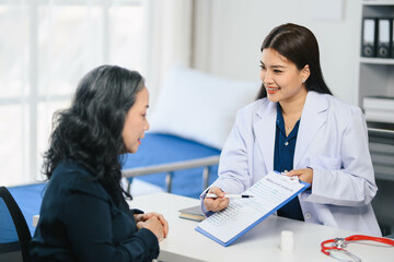 Fototapeta premium Elder woman is sitting at a desk with a clipboard in front of her