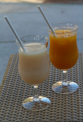 Iced orange juice and iced lychee juice on a rattan tray