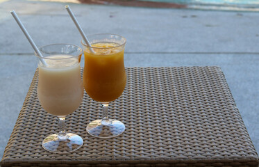 Iced orange juice and iced lychee juice on a rattan tray