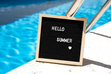 Hello summer text on chalkboard on pool background on summer sunny day