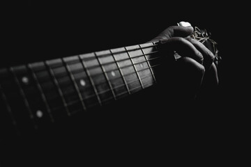 Guitarist pressing chords under lamp light