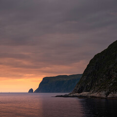 Glorious sunset off the coast of Norway, seen from cruise ship, as the sun gently illuminates the cliff face