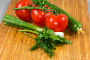 Various fresh vegetables and herbs on a wooden cutting board