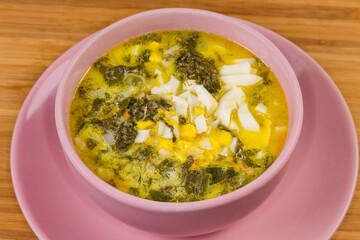 Portion of sorrel soup with chopped egg in pink bowl
