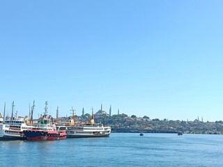 Fototapeta premium a ship with a red hull sits in the water. Istanbul City silhouette.