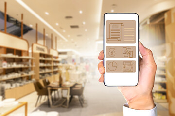 The hands of a businessman wearing a white shirt hold a mobile phone at a shopping mall. Mobile with screen for ordering products online Order items by mobile phone