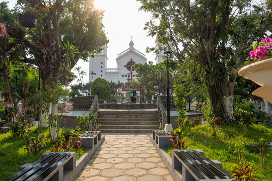 Main park with a fountain and Christian catholic church in the background in a historical city center of a small tourist town. Juayua, El Salvador.