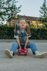 kid girl playing surf skate or skateboard in headphones