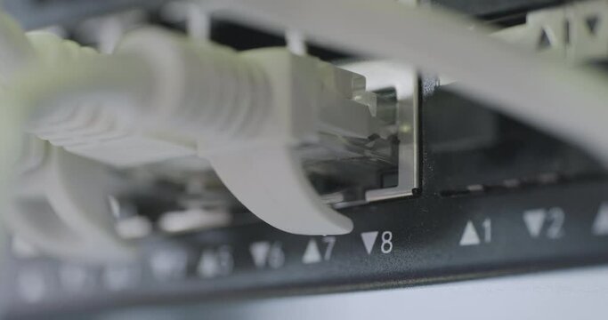 Data center, network panel, switch and connected cables, blinking green lights. Close up handheld shot, real time motion, selective focus.