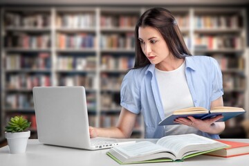 Cheerful young university student girl research in library