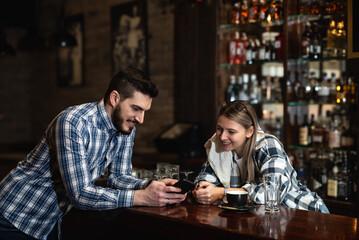 Two young people, husband and wife, Pub owners, working in their cafeteria, cleaning and calculating before opening time. Man and woman work in coffee shop, ordering drinks from delivery company
