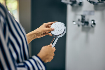 Focus on the female hand holding a shower head, and buying some bathroom accessories.