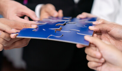 Multiethnic business people holding jigsaw pieces and merge them together as effective solution...