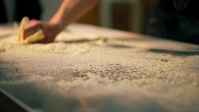 close up in a professional kitchen in a pizzeria young chef in a black uniform prepares pizza dough