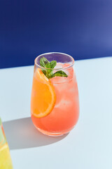 Refreshing Peach and Orange Lemonade in a Highball Glass Against a Blue Background