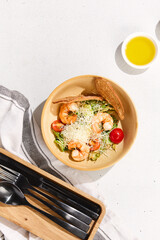 Fresh Shrimp Caesar Salad with Parmesan Cheese, Cherry Tomatoes, and Crispy Bread on White Background