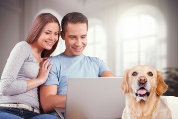 Smiling young couple sitting on sofa with laptop