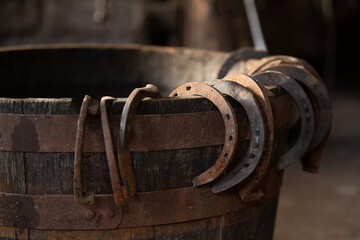 Close up photo of a wooden barrel with horseshoes hanging on the side.
