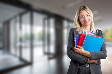 Smiling business woman with documents standing in office.