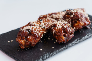 Chicken wings in soy honey sauce with sesame seeds on a black board