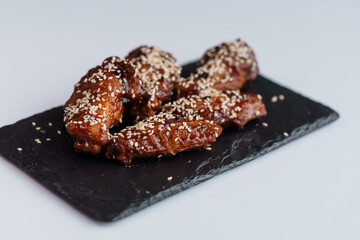 Chicken wings in soy honey sauce with sesame seeds on a black board