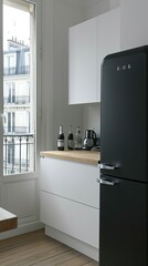 Modern kitchen interior with white cabinets, a black refrigerator and a wooden countertop, with bright light coming in from the window.