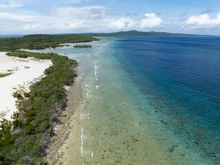 Early morning sunlight shines on the coast of a remote island, Pulau Selu, in the Tanimbar Islands of Indonesia. This tropical area harbors beautiful coral reefs and a wide diversity of fishes.