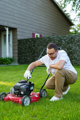 Young man using lawn mower outdoor and checking oil