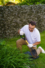 Man transplanting beautiful flowers into soil outdoors on sunny day. Gardening time