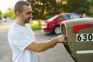 Young man getting his mail from his mailbox.