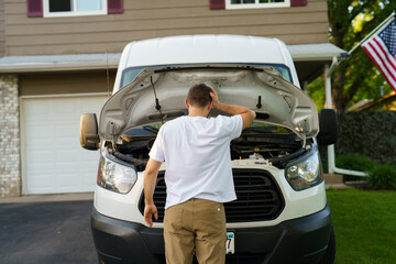 Young stressed man having trouble with his broken car looking in frustration at failed engine