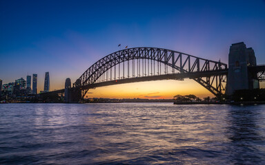 Naklejka premium Long exposure of the amazing Sydney Harbour Bridge and Sydney's Downtown from the north bank namely Mattawunga, at sunset, Australia