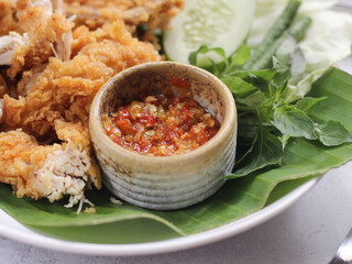 Sambal Geprek, made from chili sauce made from garlic and chili seasoned with salt, sugar and flavoring then doused with hot oil. Selective focus, oily texture