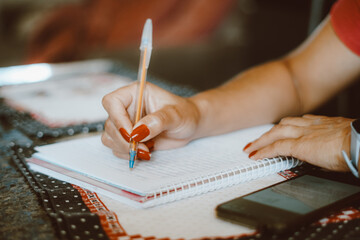 Woman studying and writing in notebook at home.