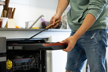 young man putting a dishwasher in his house after a meal. Man doing housework.